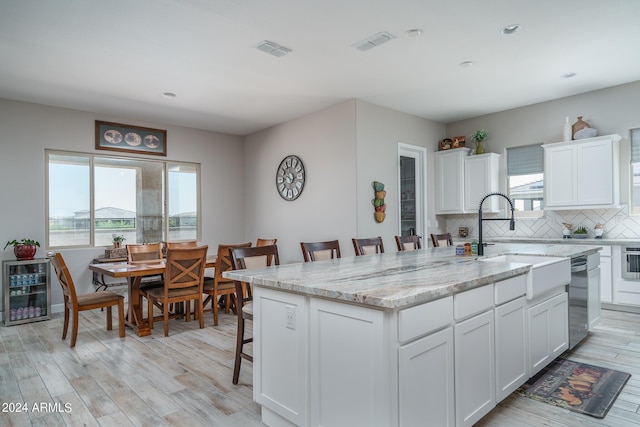 kitchen with a kitchen bar, sink, white cabinets, and a center island with sink