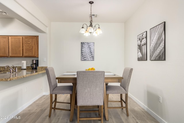 dining area featuring sink, a chandelier, and light hardwood / wood-style floors