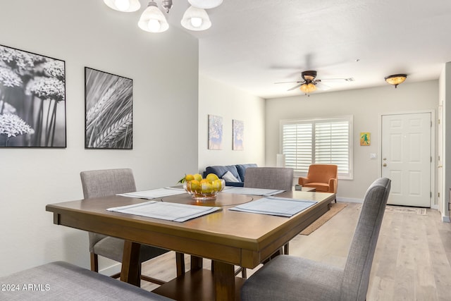 dining area with light hardwood / wood-style flooring and ceiling fan with notable chandelier