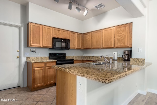 kitchen with kitchen peninsula, light stone countertops, black appliances, and sink