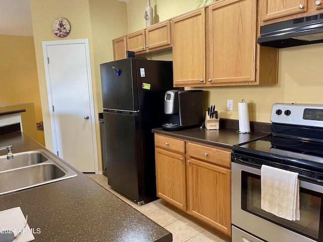 kitchen with stainless steel electric range oven, freestanding refrigerator, a sink, under cabinet range hood, and dark countertops