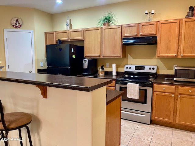 kitchen with a breakfast bar, a center island, electric range, black fridge, and light tile patterned flooring