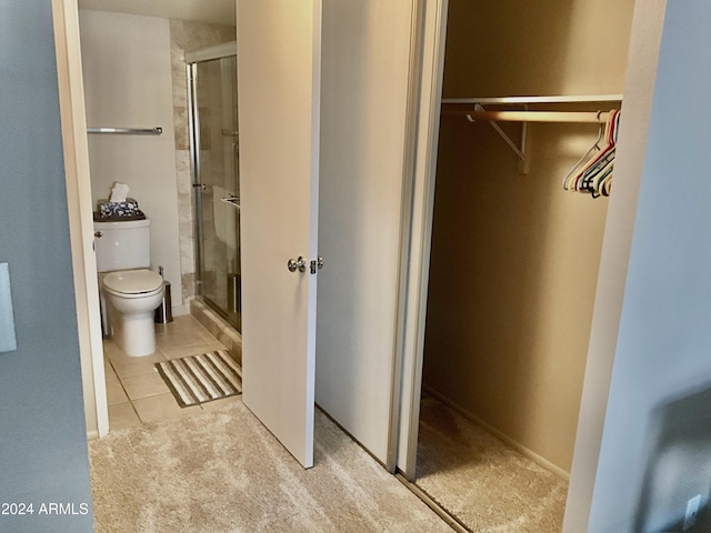 bathroom with tile patterned flooring, an enclosed shower, and toilet