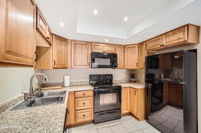 kitchen featuring sink, light stone counters, a tray ceiling, light tile patterned floors, and black appliances