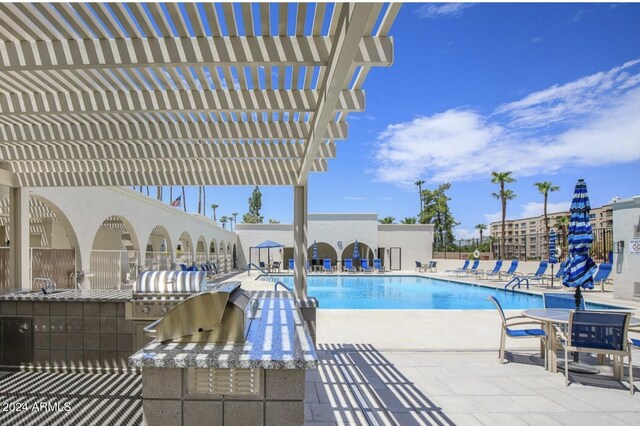 view of swimming pool with exterior kitchen, a pergola, and a patio