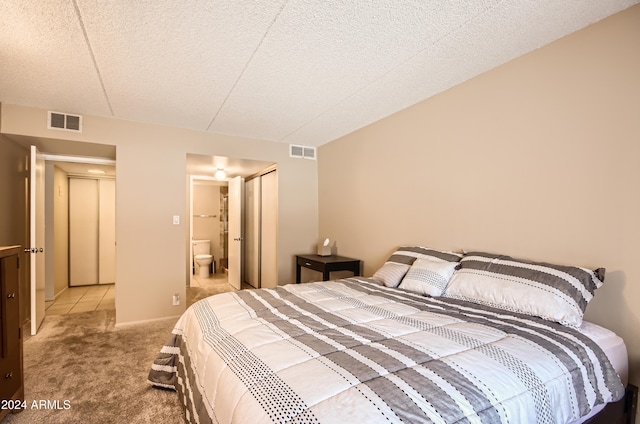 bedroom featuring light carpet, a textured ceiling, and ensuite bathroom