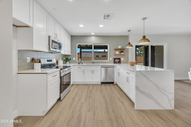 3614 W Danbury Dr, Glendale, AZ 85308 - kitchen with appliances with stainless steel finishes, a peninsula, light wood-style flooring, backsplash, and recessed lighting