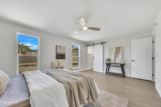 3614 W Danbury Dr, Glendale, AZ 85308 - bedroom with a barn door, light wood-style flooring, and a ceiling fan