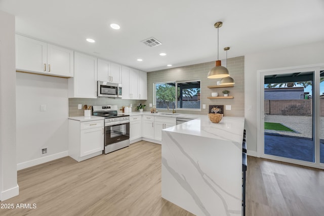 3614 W Danbury Dr, Glendale, AZ 85308 - kitchen featuring appliances with stainless steel finishes, decorative backsplash, a peninsula, white cabinets, and light stone countertops