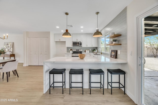 3614 W Danbury Dr, Glendale, AZ 85308 - kitchen with appliances with stainless steel finishes, backsplash, white cabinetry, light wood-type flooring, and a peninsula