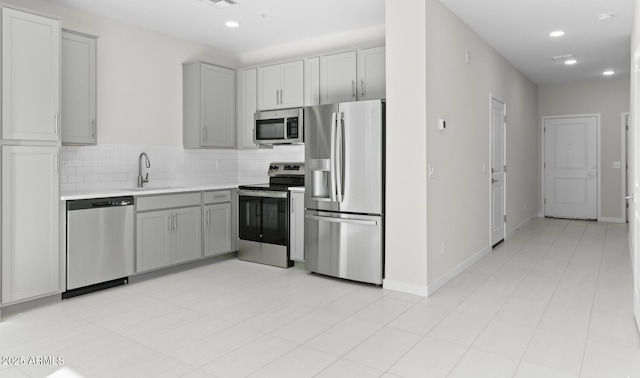 kitchen featuring stainless steel appliances, sink, gray cabinetry, and backsplash