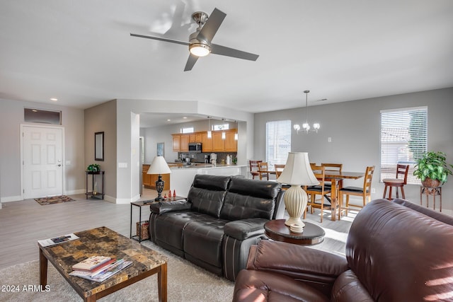 living room featuring light hardwood / wood-style floors and ceiling fan with notable chandelier