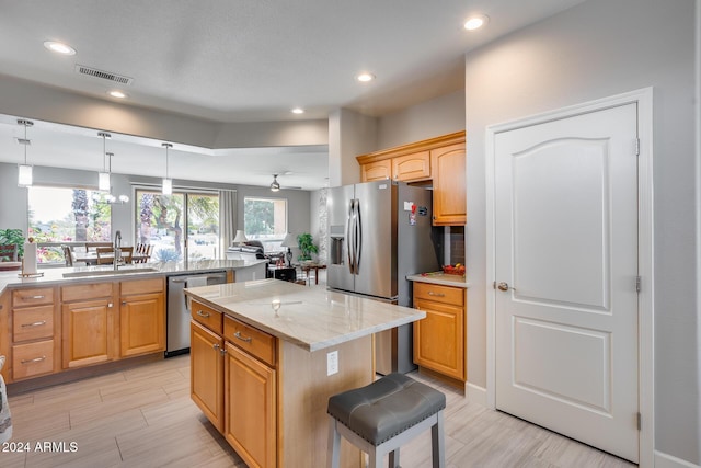 kitchen featuring a center island, sink, stainless steel appliances, light stone counters, and a kitchen bar