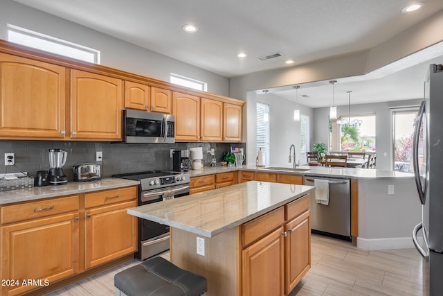 kitchen with sink, a center island, hanging light fixtures, decorative backsplash, and appliances with stainless steel finishes