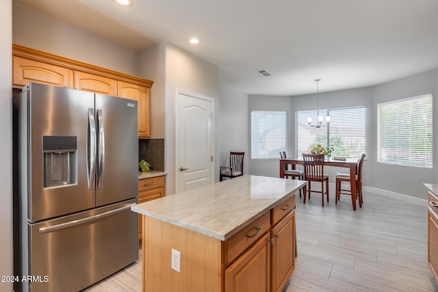 kitchen with a center island, hanging light fixtures, decorative backsplash, stainless steel fridge, and a chandelier