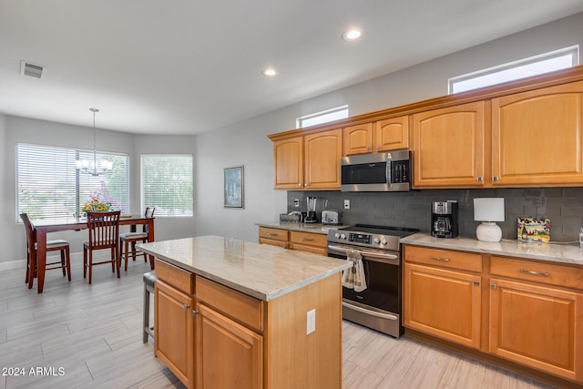 kitchen with light stone counters, stainless steel appliances, decorative light fixtures, a chandelier, and a center island