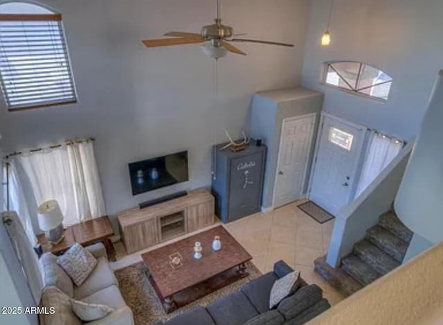 living room with ceiling fan, plenty of natural light, and a high ceiling