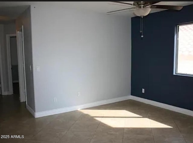 tiled empty room featuring ceiling fan