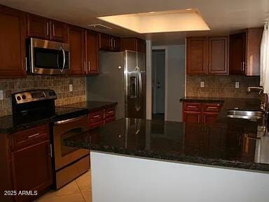 kitchen featuring light tile patterned flooring, appliances with stainless steel finishes, kitchen peninsula, and sink