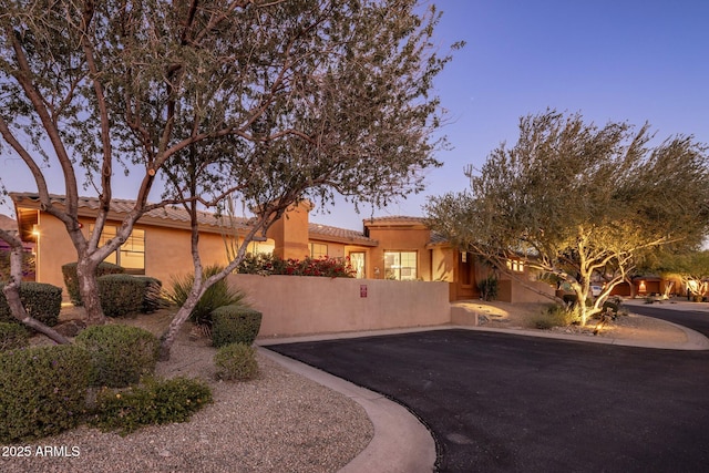 view of front of home with a tiled roof, fence, and stucco siding