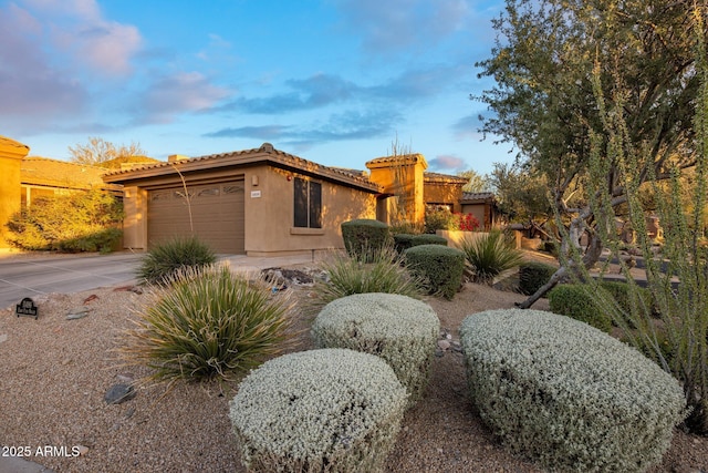 view of property exterior with a tile roof, concrete driveway, a garage, and stucco siding