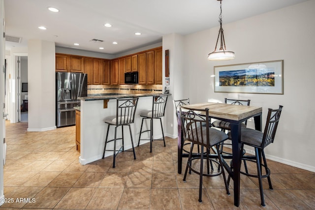 kitchen with visible vents, stainless steel fridge with ice dispenser, black microwave, dark countertops, and brown cabinets