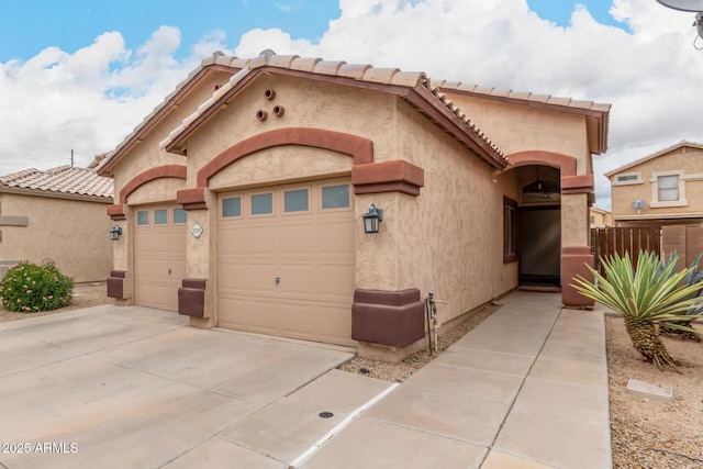 view of front facade featuring a tiled roof, a garage, driveway, and stucco siding