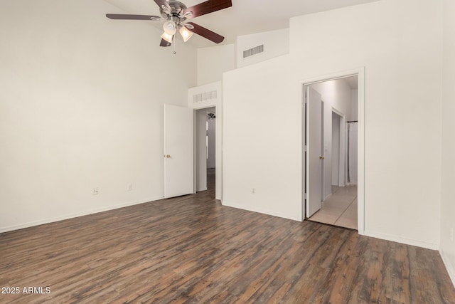 unfurnished bedroom with visible vents, connected bathroom, baseboards, wood finished floors, and high vaulted ceiling