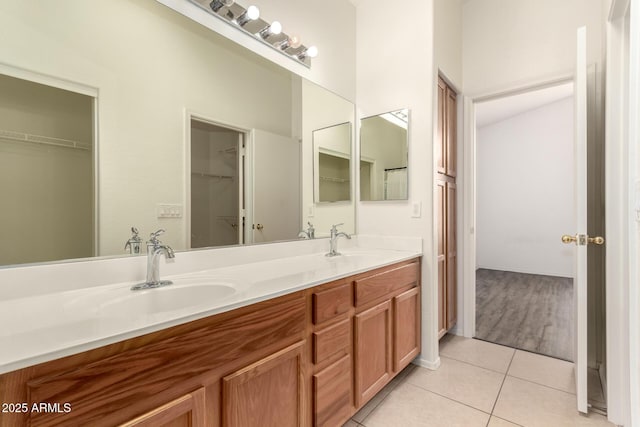 bathroom with tile patterned floors, a spacious closet, double vanity, and a sink