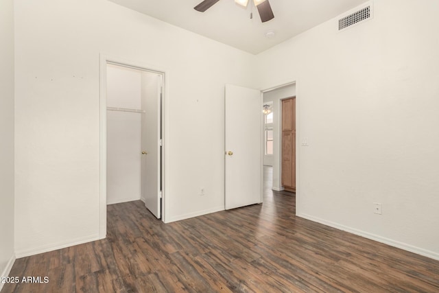 unfurnished bedroom with a spacious closet, visible vents, baseboards, a closet, and dark wood-style flooring