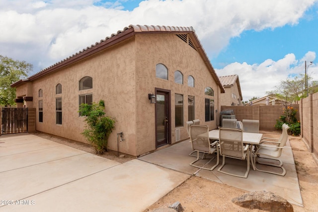 back of property with a tiled roof, a patio area, a fenced backyard, and stucco siding