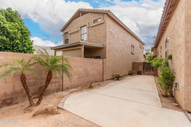 exterior space with stucco siding, fence private yard, and a gate