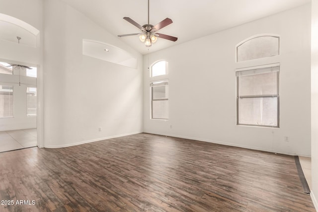 empty room with baseboards, high vaulted ceiling, wood finished floors, and a ceiling fan