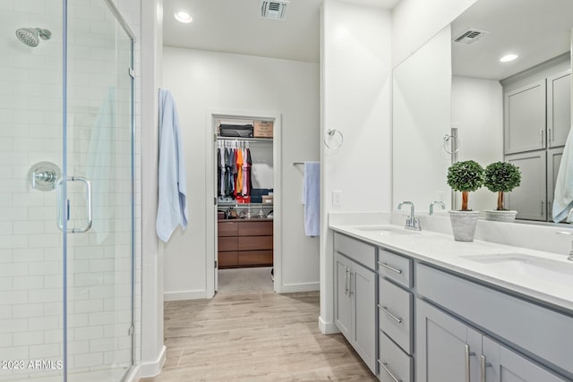 bathroom with vanity, a shower with door, and wood-type flooring