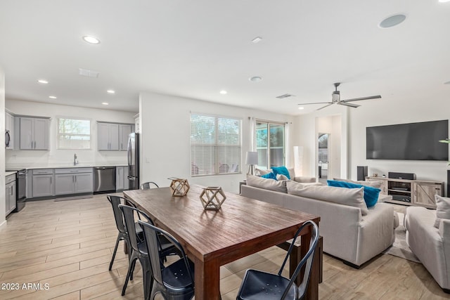 dining area with ceiling fan, sink, and light wood-type flooring