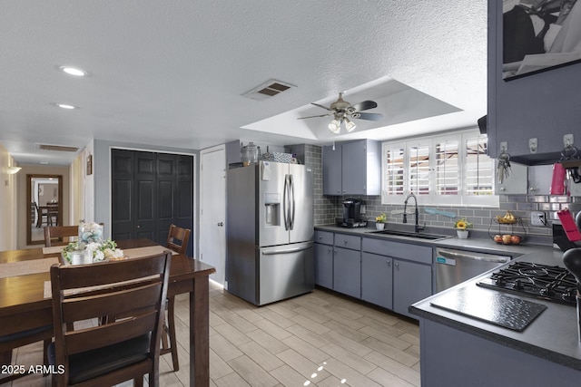 kitchen featuring sink, a textured ceiling, appliances with stainless steel finishes, ceiling fan, and backsplash