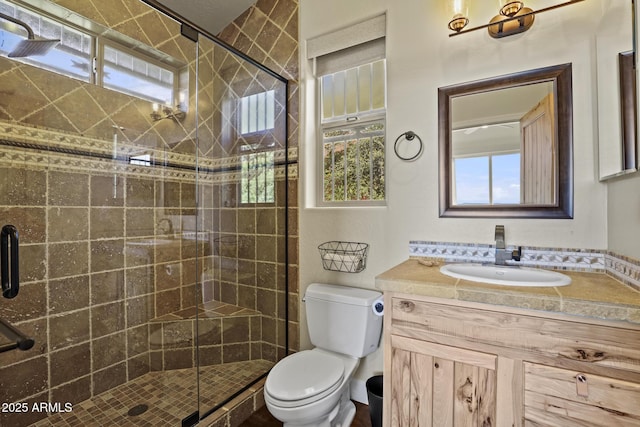 bathroom featuring plenty of natural light, toilet, a shower with door, and vanity