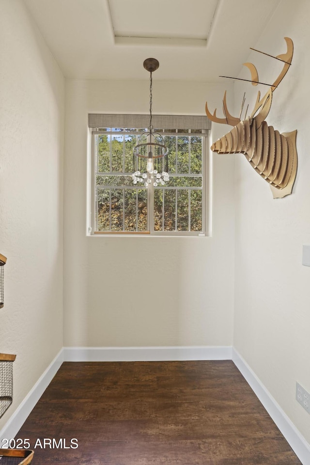 unfurnished dining area featuring a healthy amount of sunlight, a chandelier, and dark hardwood / wood-style floors