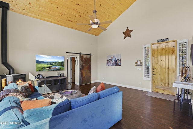 living room featuring wooden ceiling, a wood stove, dark hardwood / wood-style floors, ceiling fan, and a barn door