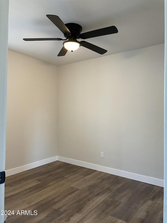 spare room featuring baseboards and dark wood-style flooring