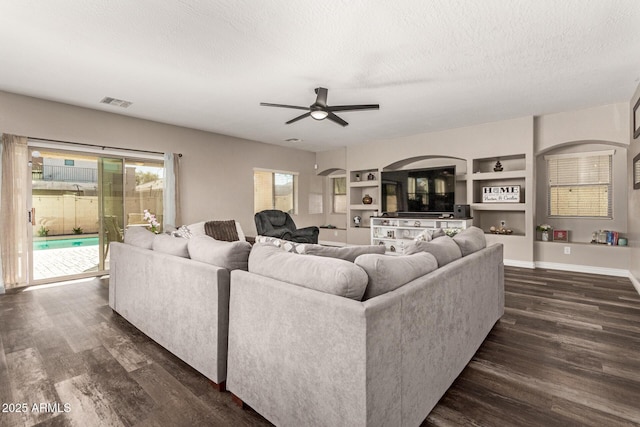 living room featuring dark hardwood / wood-style flooring, built in features, and ceiling fan