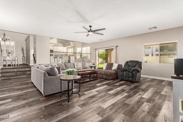 living room with a textured ceiling, ceiling fan with notable chandelier, and dark wood-type flooring