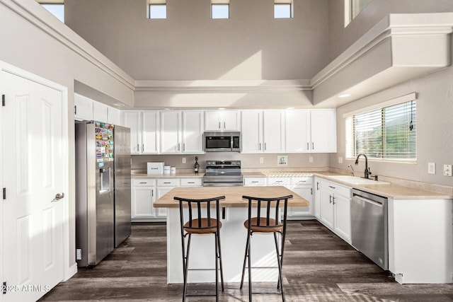 kitchen featuring sink, white cabinets, a breakfast bar, a kitchen island, and appliances with stainless steel finishes