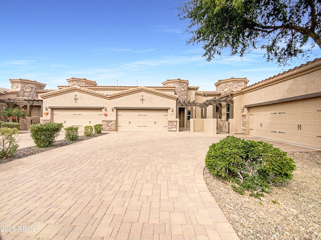 mediterranean / spanish house featuring decorative driveway, a tile roof, stucco siding, a garage, and stone siding