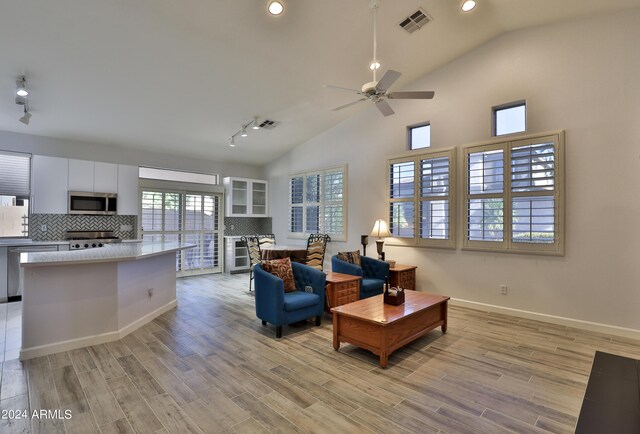 living room with high vaulted ceiling, plenty of natural light, ceiling fan, and light hardwood / wood-style floors