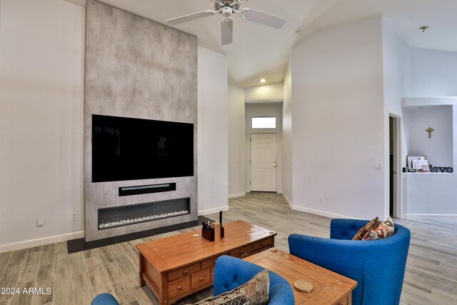 living room featuring high vaulted ceiling, a large fireplace, ceiling fan, and light hardwood / wood-style floors