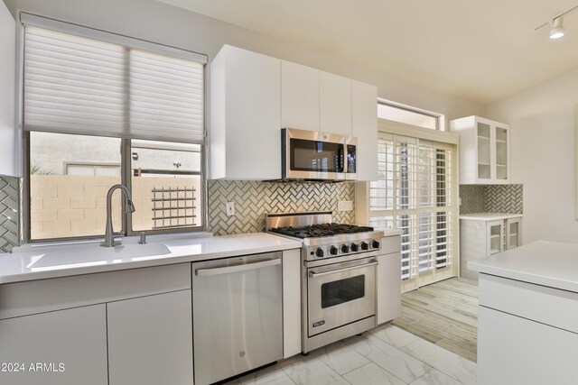 kitchen with backsplash, sink, stainless steel appliances, and white cabinets