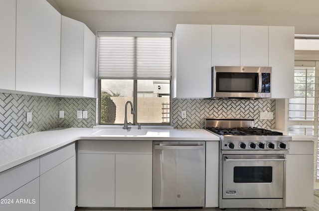 kitchen with white cabinets, stainless steel appliances, decorative backsplash, and sink