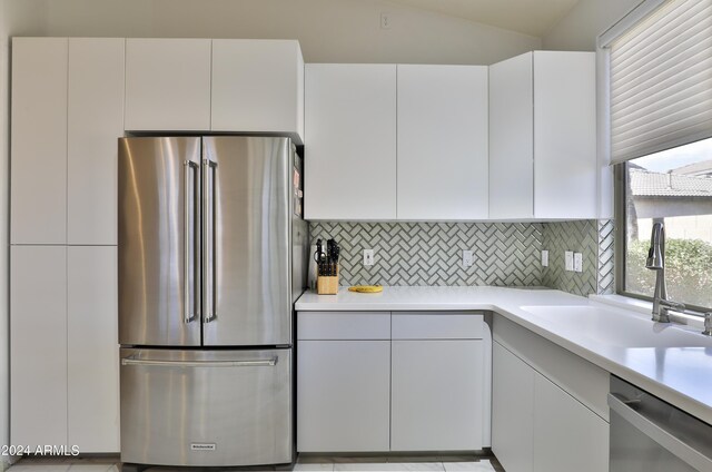 kitchen featuring white cabinetry, sink, decorative backsplash, appliances with stainless steel finishes, and lofted ceiling