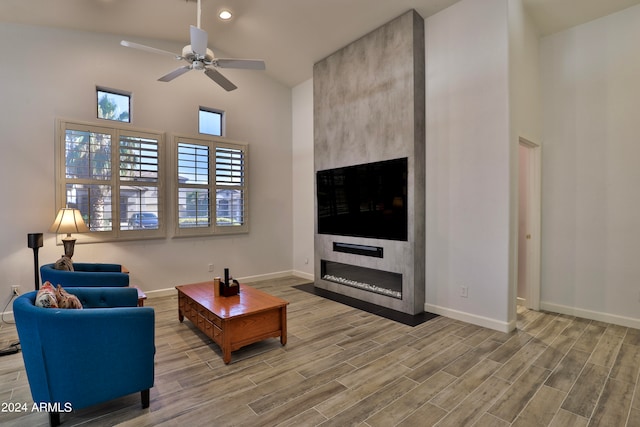 living room with ceiling fan, hardwood / wood-style floors, high vaulted ceiling, and a fireplace